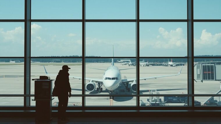 Silhouette at airport window viewing plane